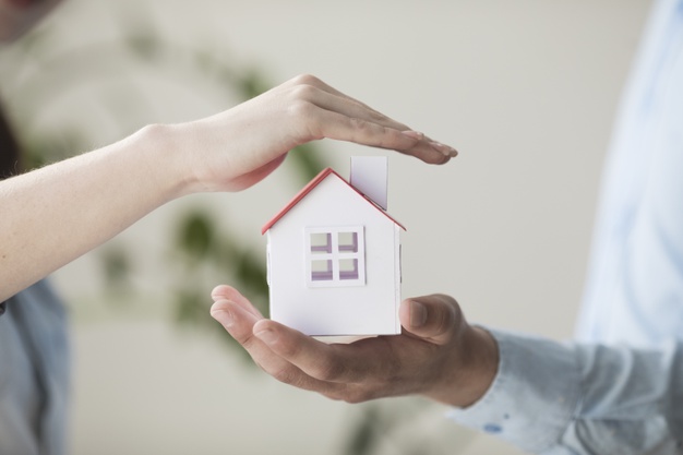 mãos segurando miniatura de casa